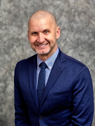 Headshot of smiling bald man in suit