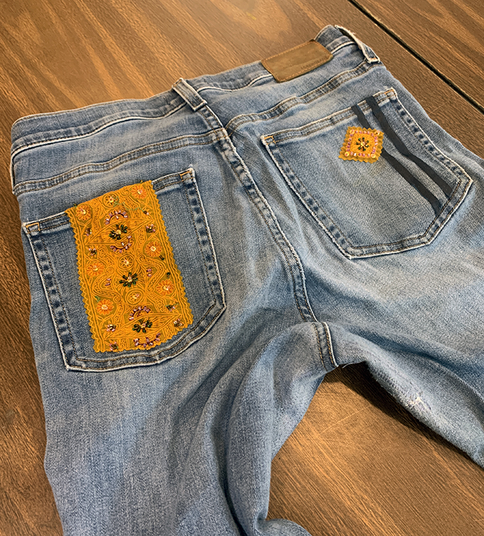 Denim jeans with mended pockets that feature added fabric and gems.