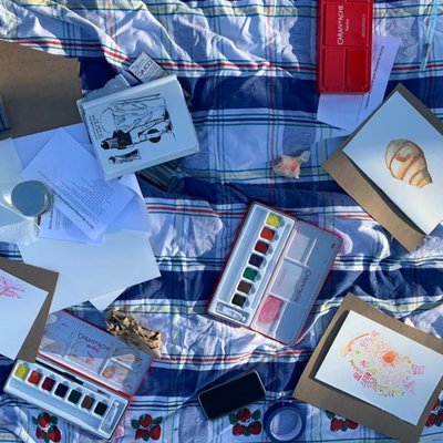 illustrations and painting supplies on top of a picnic blanket