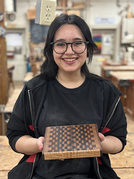 Ashley Veliz Acevedo holding a handmade cutting board